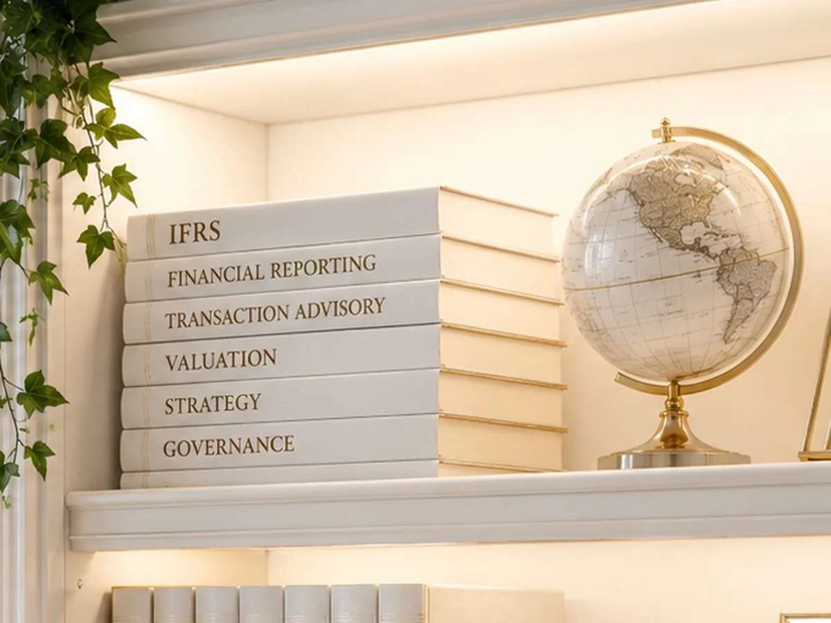 A lit shelf of reference volumes titled IFRS, Financial Reporting, Transaction Advisory, Valuation, Strategy and Governance, beside a brass globe.